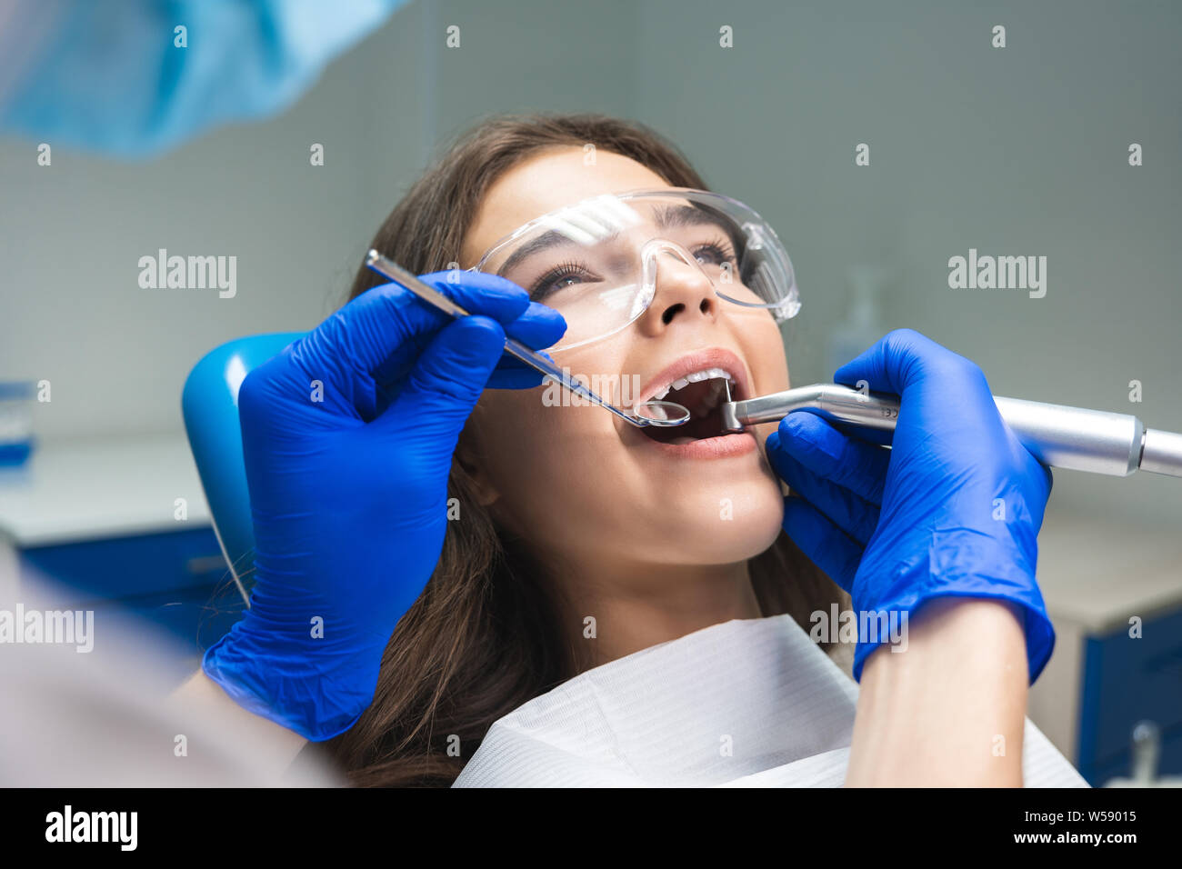 dentist in mask filling the patient's root canal while she is lying on