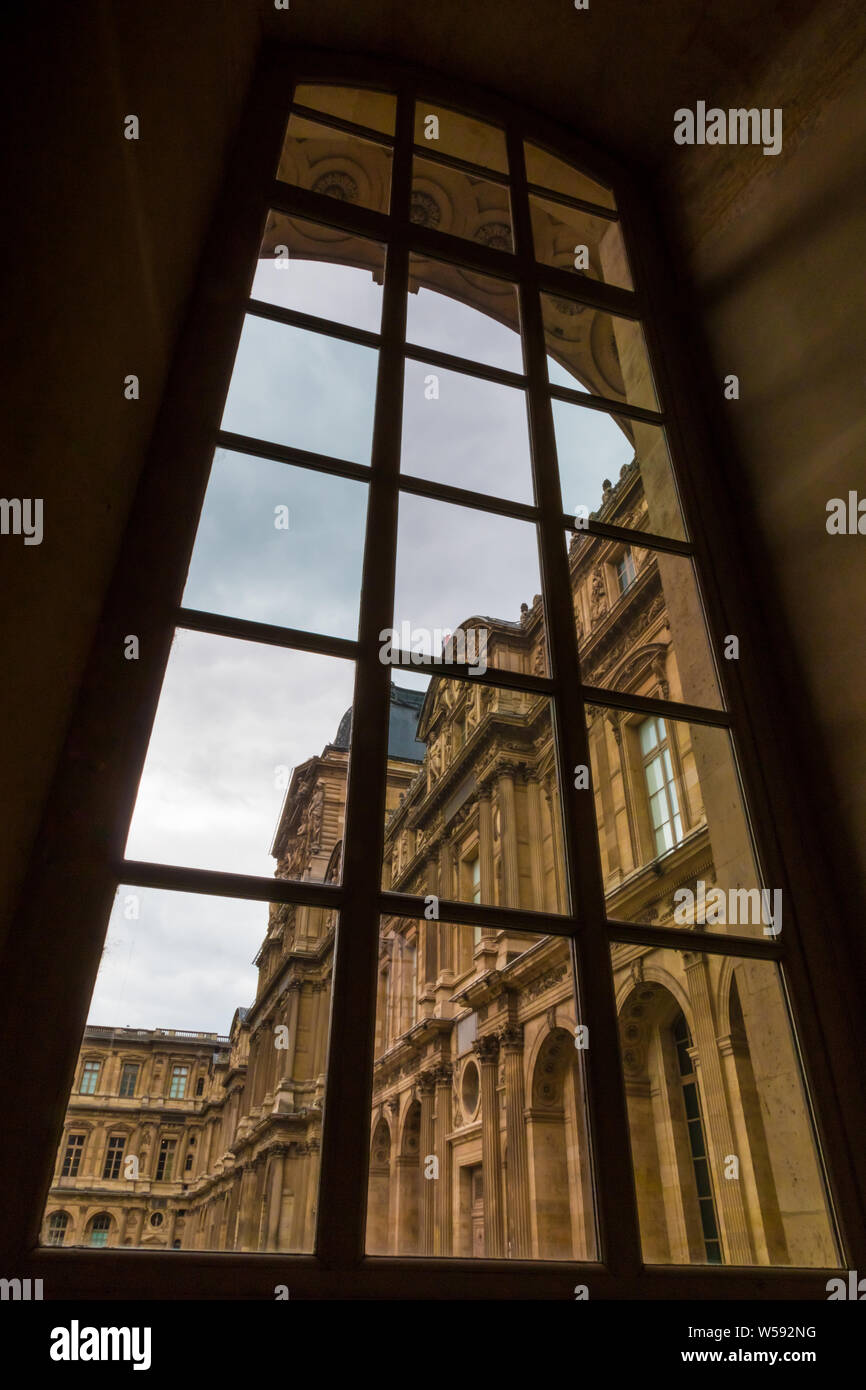 Artistic picture of the Sully Wing at the Quadrangular Courtyard of the Louvre building through a big French Renaissance style window from inside the... Stock Photo