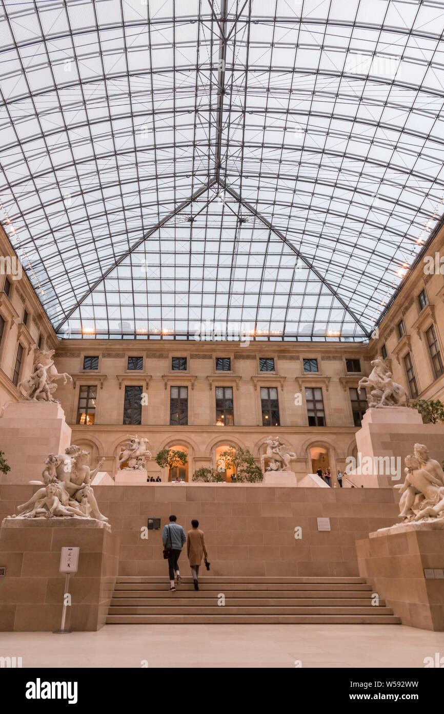 Great picture of the sculpture garden known as Cour Marly in the Richelieu wing of the Louvre Museum. Two visitors are going up the stairs of the... Stock Photo
