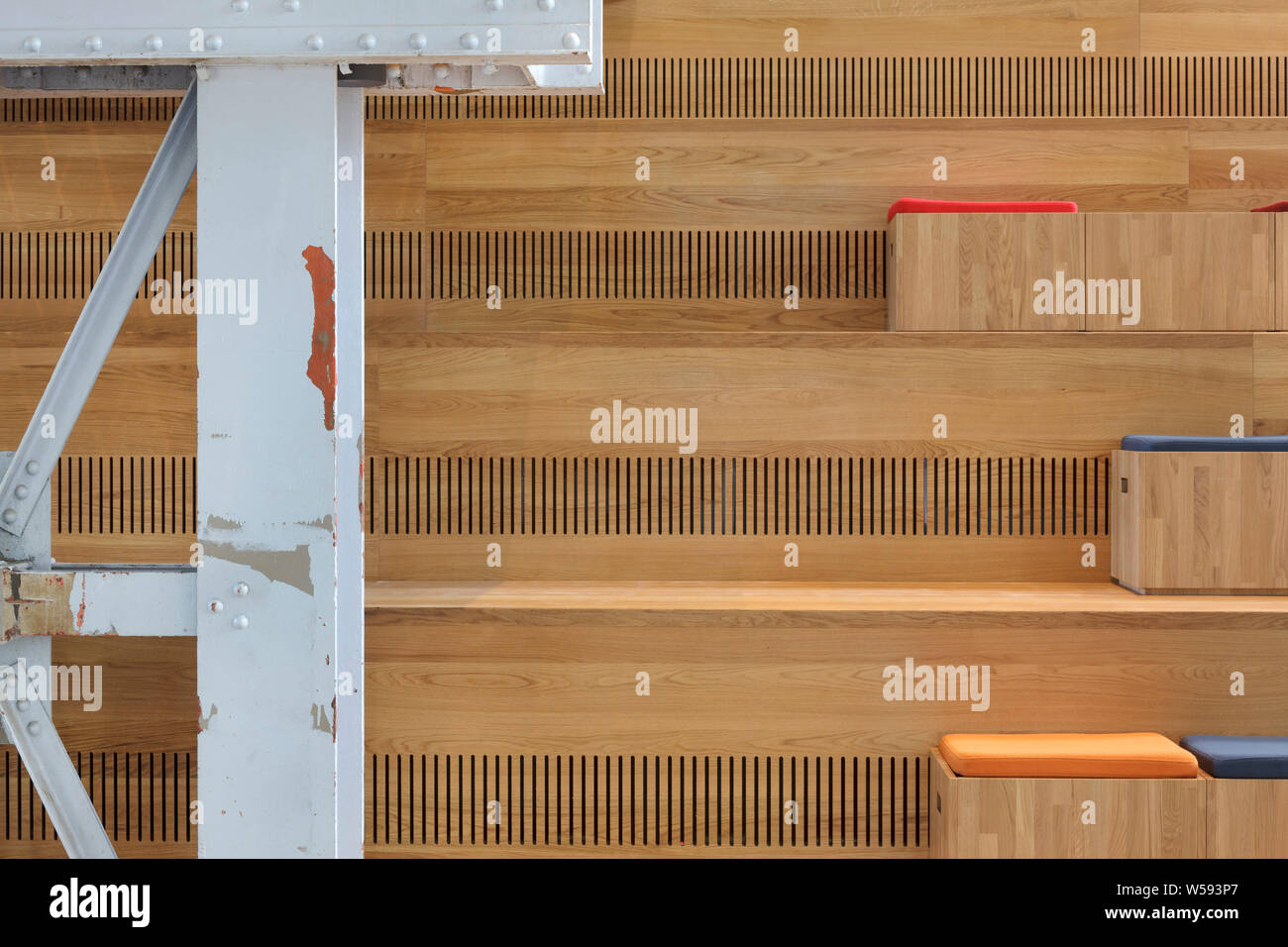 Detail of timber seating on main staircase with cusions, and distressed steel beam in foregroud with flaking red and white paint. Bibliotheek LocHal, Stock Photo