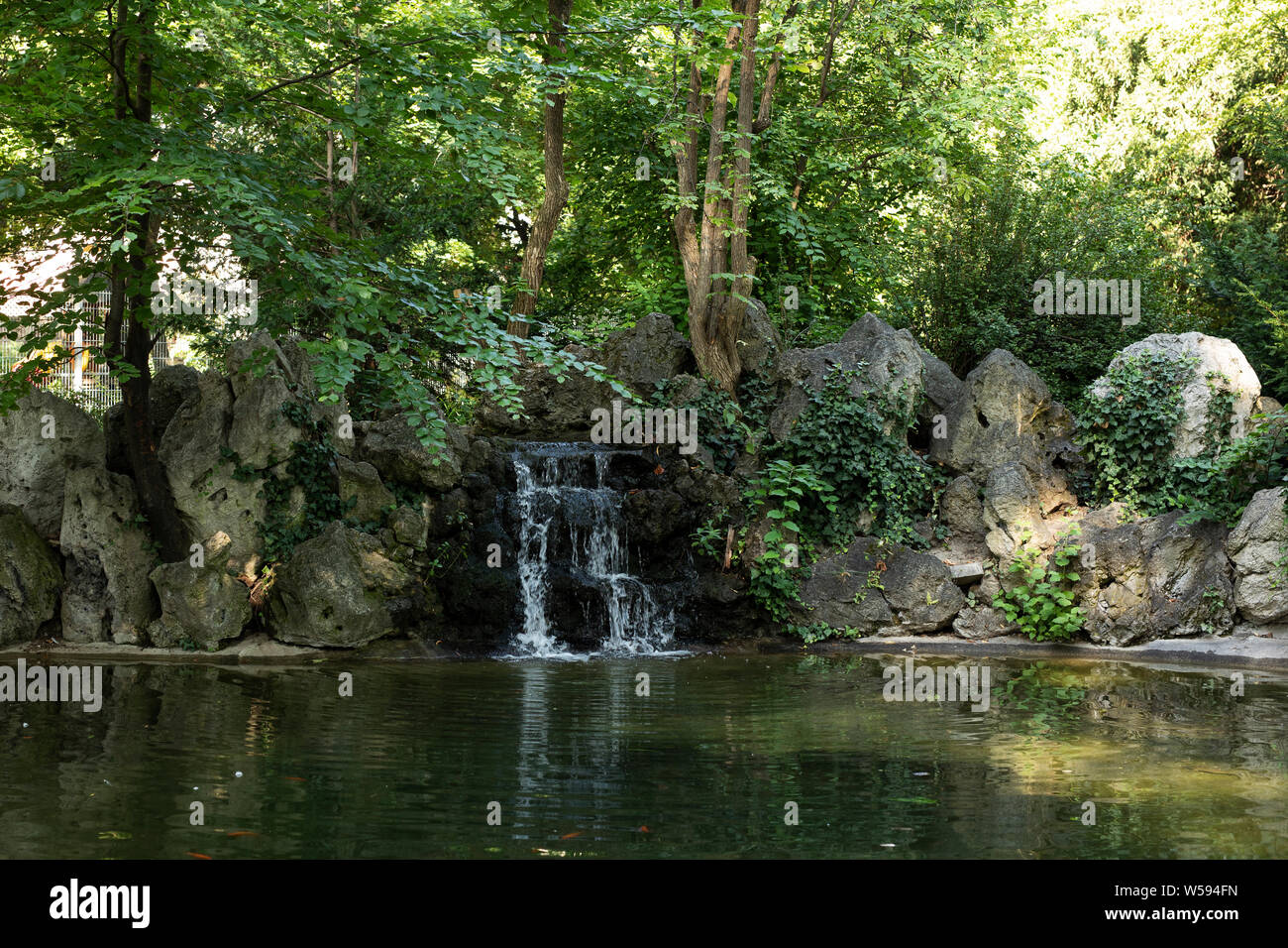 A pond with a small waterfall in the park (Liechtensteinpark) behind the Liechtenstein Garden Palace in Vienna, Austria. Stock Photo
