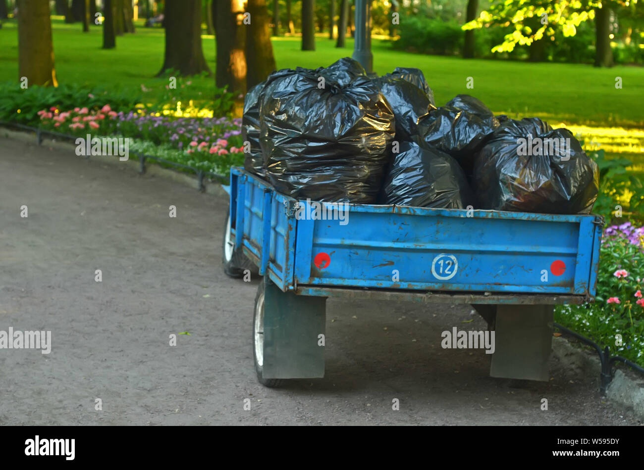 Trailer with many bags of plant garbage in the garden.Periodic garbage