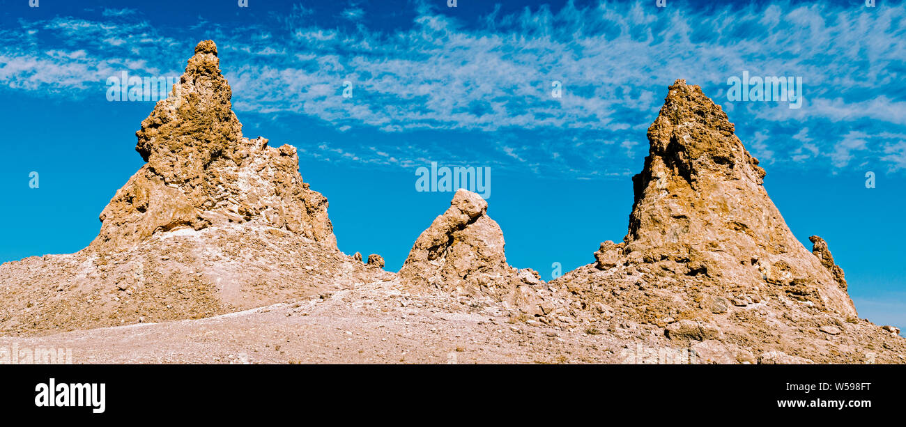 There rocky pinnacles against light blue skies with white clouds. Stock Photo