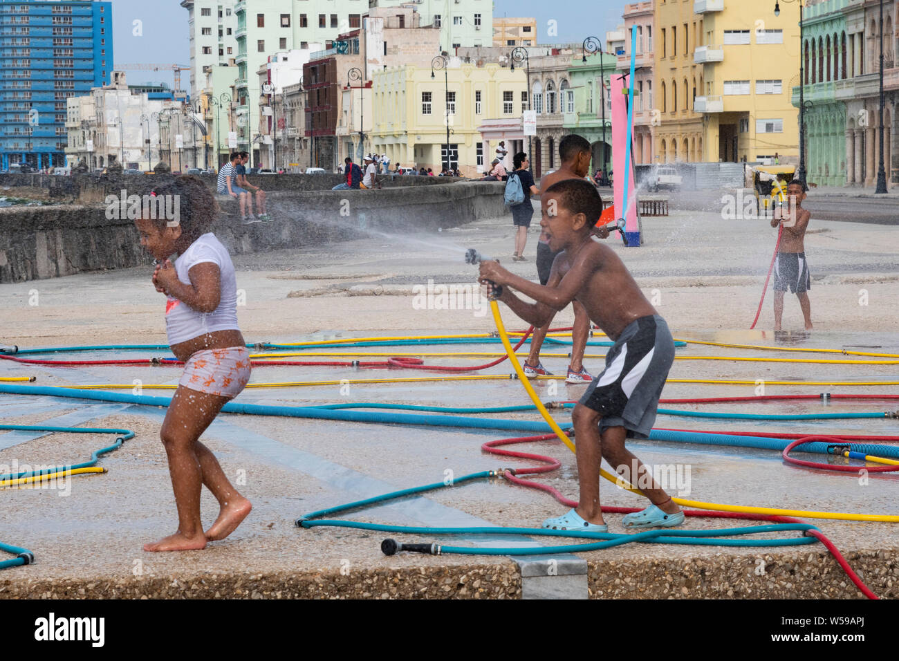 Cuban children spray water hoses - part of artwork installation on the Malecon in Havana, Cuba from the Biennial art exposition Stock Photo