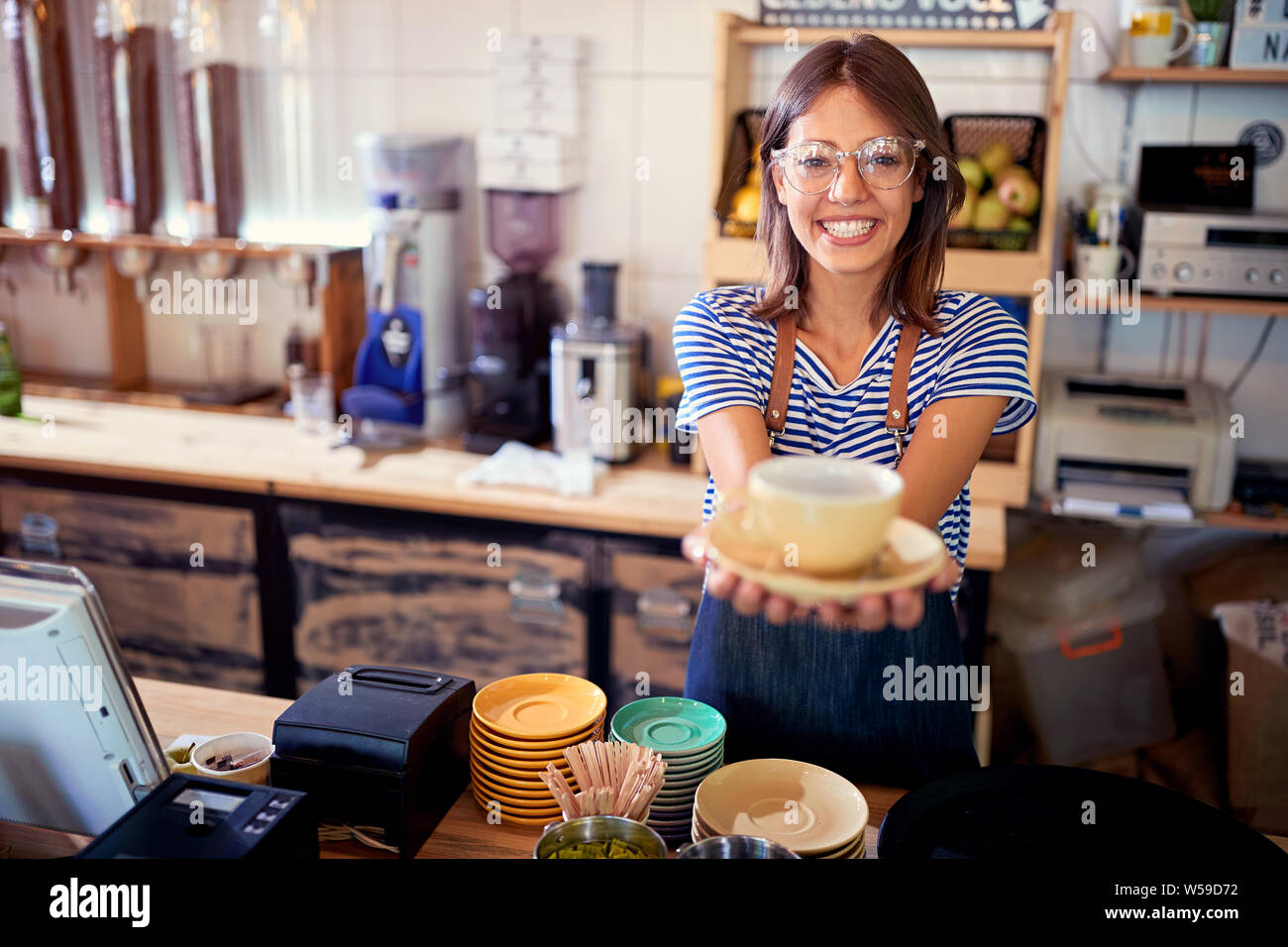 Smiling woman in cafe serving customer with coffee. Stock Photo