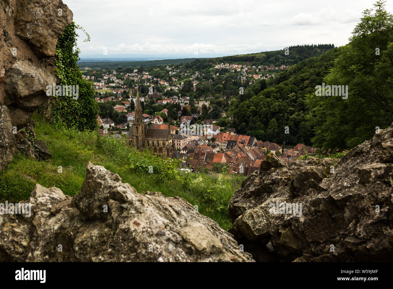 Overlooking the quaint Alsatian city of Thann, France, including the medieval St. Theobald's Church, from the ruins of Engelbourg Castle. Stock Photo