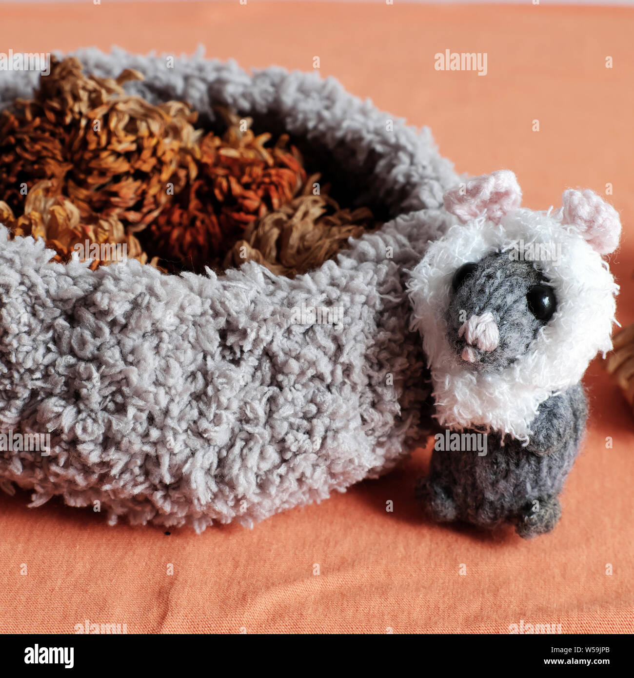 cute mice stand near basket of dried flower on orange  background, woolen small rat knit from yarn in free time of craftsmanship Stock Photo