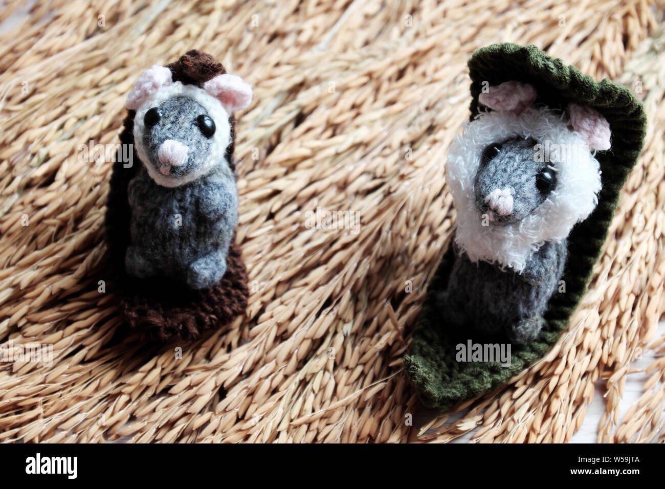 Two cute mouse lay down to relax on sheaf of paddy background, handmade product woolen small rat knit from yarn in free time Stock Photo