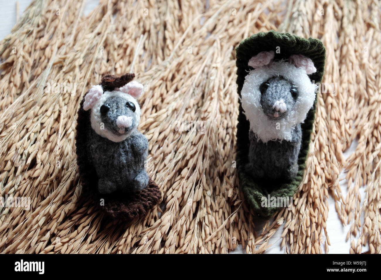 Two cute mouse lay down to relax on sheaf of paddy background, handmade product woolen small rat knit from yarn in free time Stock Photo