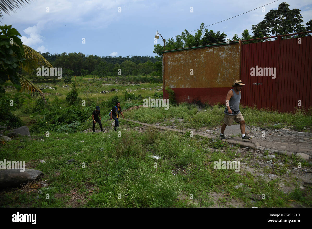 July 25, 2019, Talisman, Chiapas, Mexico: A Guatemalan ''pollero'' (smuggler) leads openly two of his clients into Mexican territory from el Limon village into Talisman on Thursday, even as Guatemala signed a treaty with the US designating it a 'safe'' country for migrants. Credit: Miguel Juarez Lugo/ZUMA Wire/Alamy Live News Stock Photo