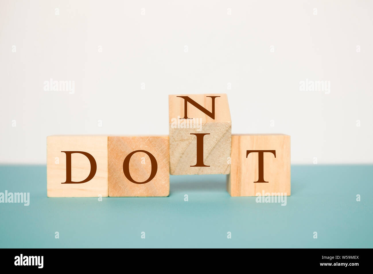 Hand flipping one wooden cube to change the word Don't for Do it on neutral background Stock Photo