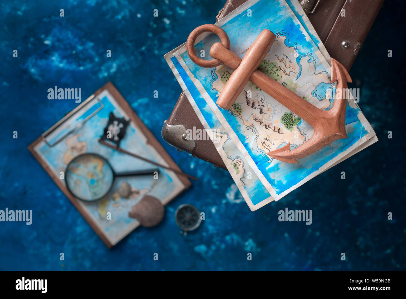 Anchor and a treasure map on a suitcase. Ready to go for an adventure flat lay with copy space. Stock Photo
