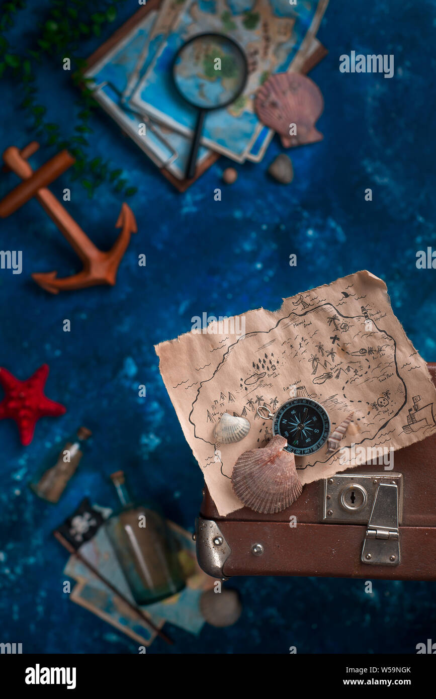 Treasure map with seashells on a suitcase. Ready to go for an adventure flat lay with copy space. Stock Photo