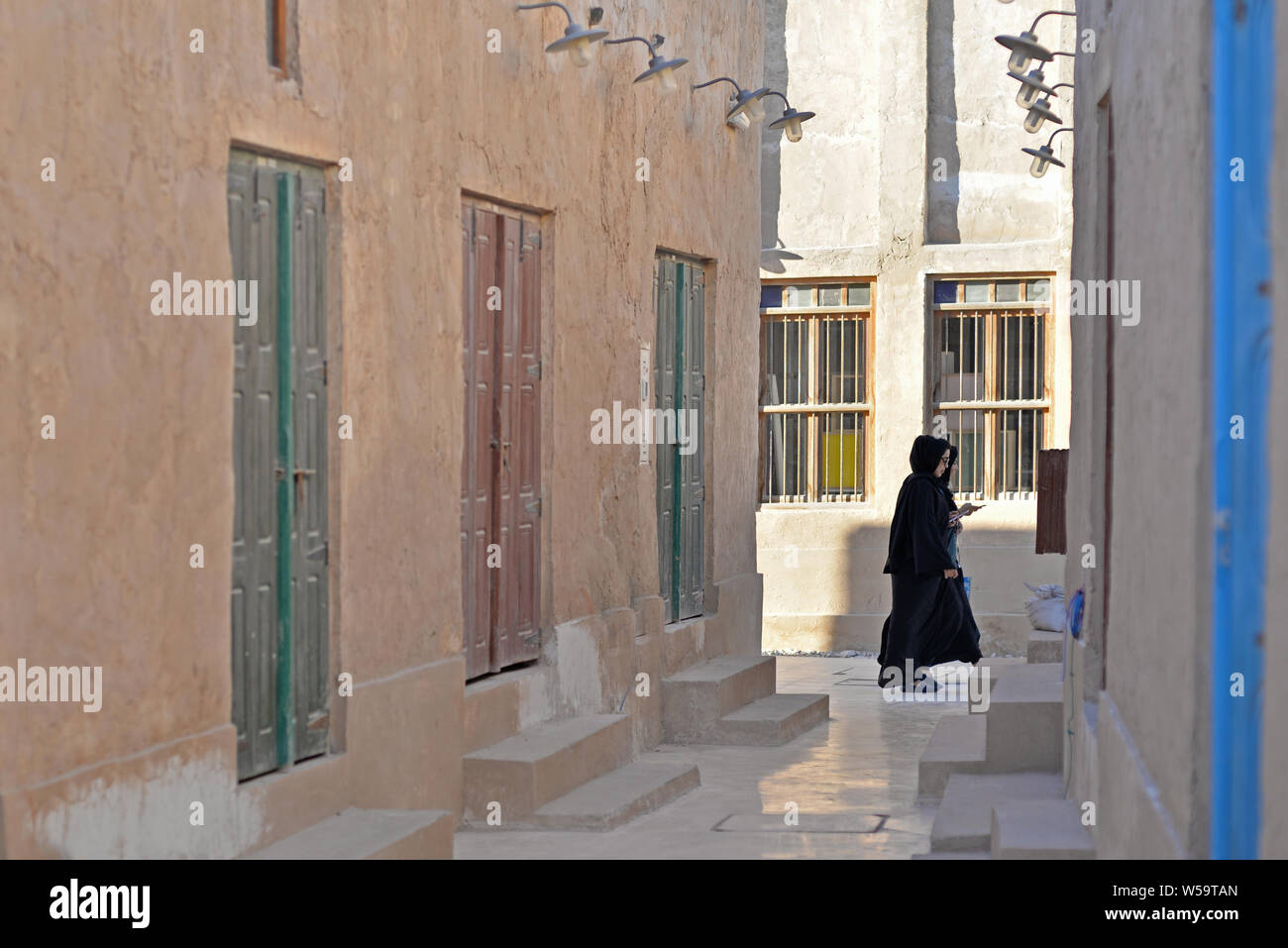 AL WAKRAH, QATAR - FEBRUARY 5, 2016:  One qatari woman wearing abaya at Wakrah old souq. Taken at the end of a winter afternoon Stock Photo