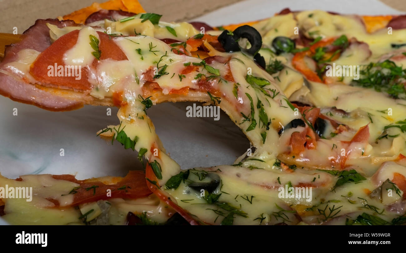 Hunting pizza with sausage, beef, tomatoes and olives on the table