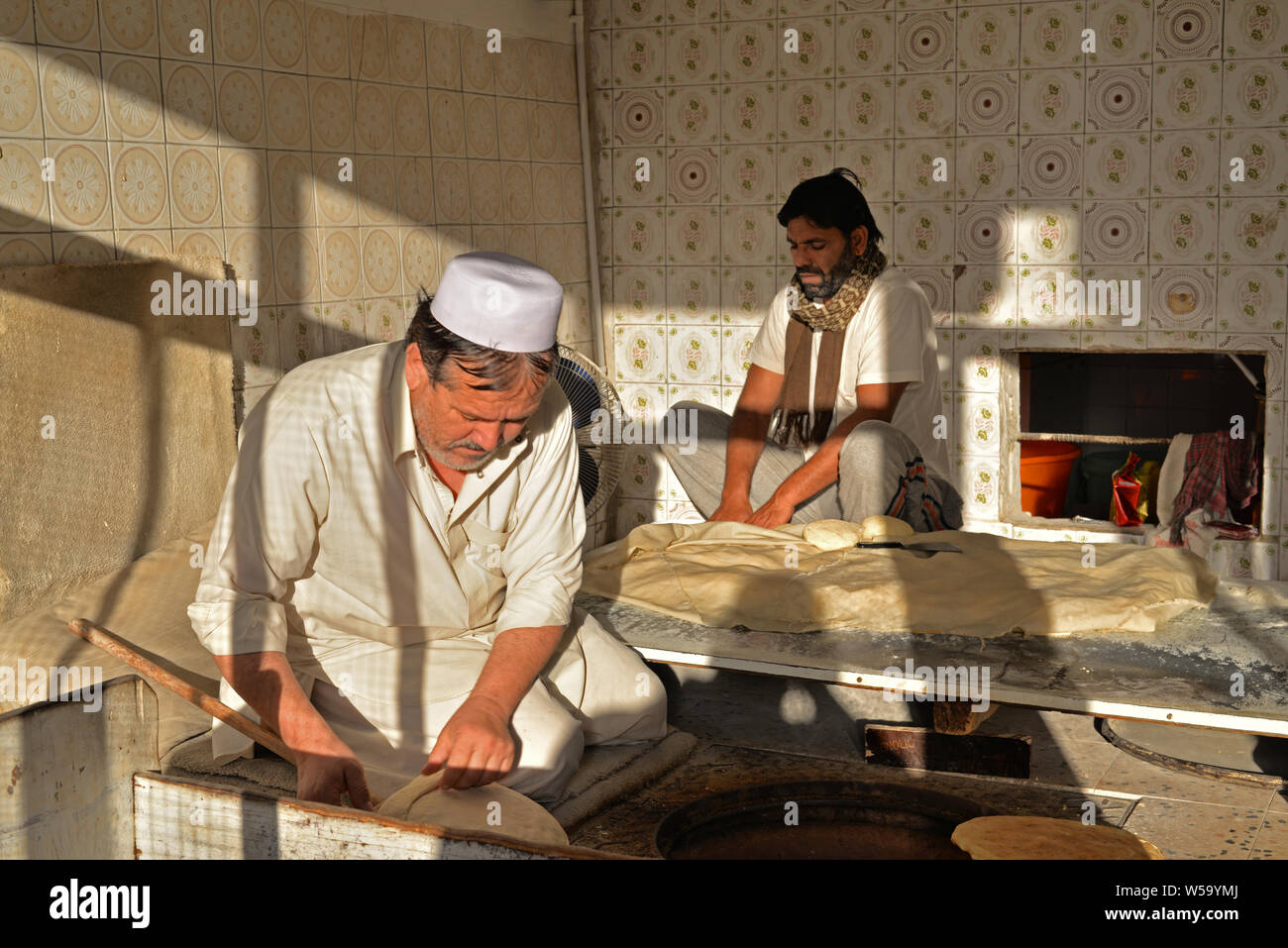 DOHA, QATAR - FEBRUARY 6, 2016: Two Pakistani bakers making bread in a traditional bakery shop in a popular district of Doha. Taken at the end of a wi Stock Photo