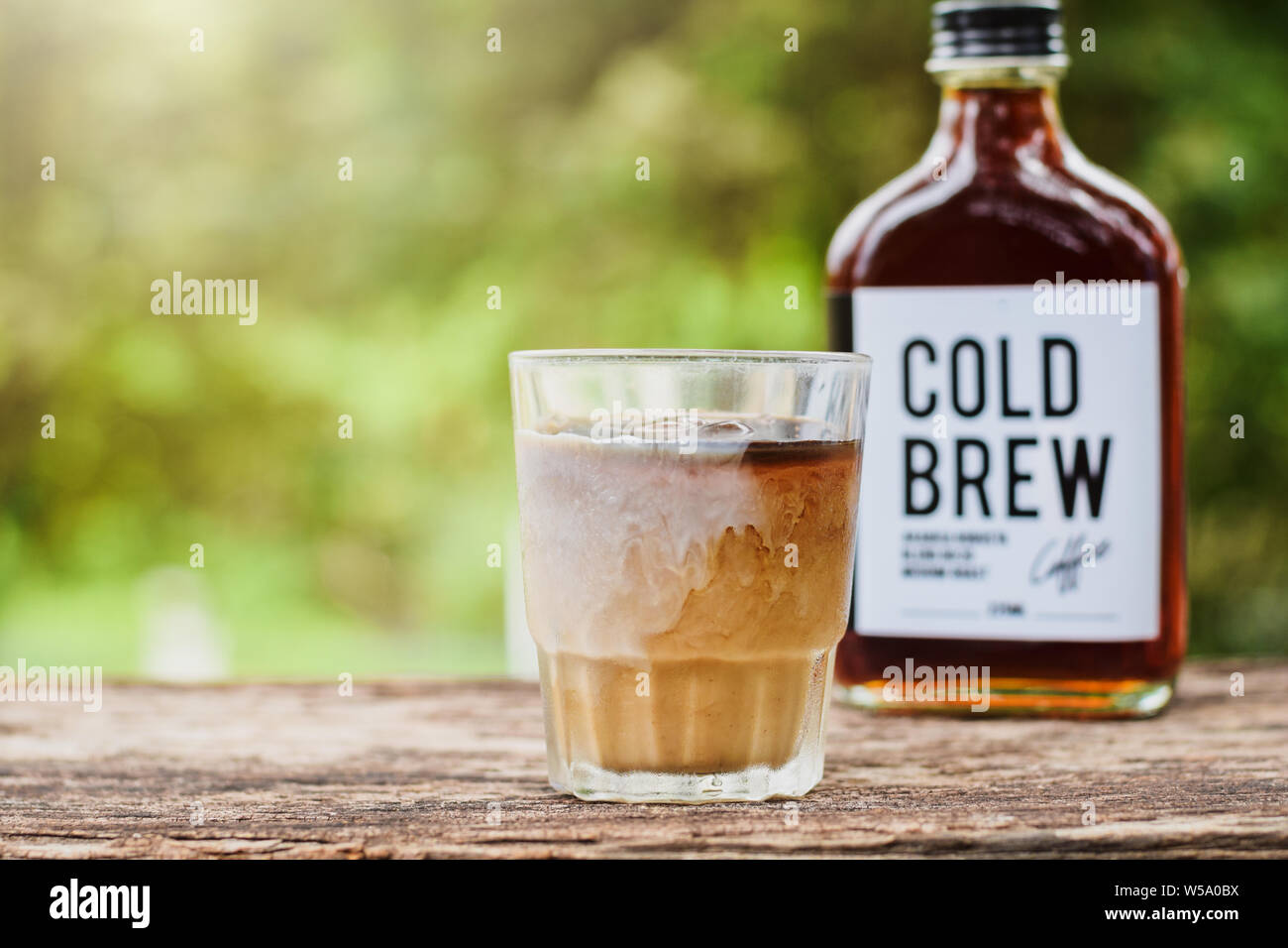 Cold brew coffee with milk on a table outside with cold-brew coffee in a glass bottle for take away Stock Photo