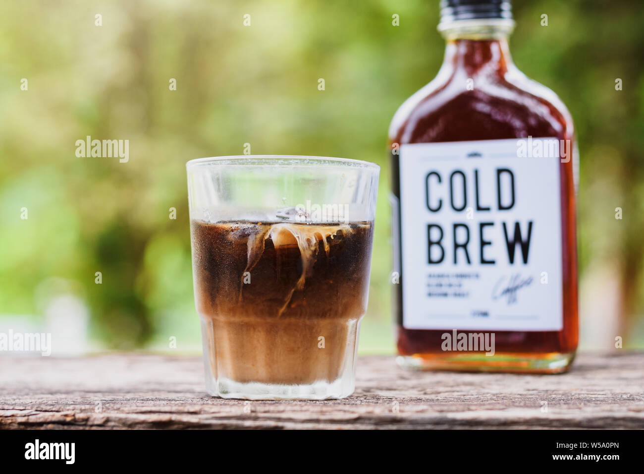 Cold brew coffee with milk on a table outside with cold-brew coffee in a glass bottle for take away Stock Photo