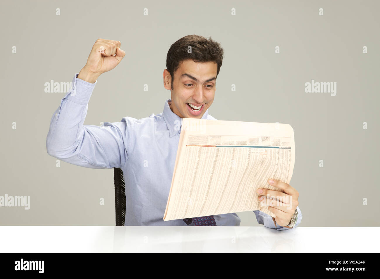 Businessman reading a newspaper and punching the air Stock Photo