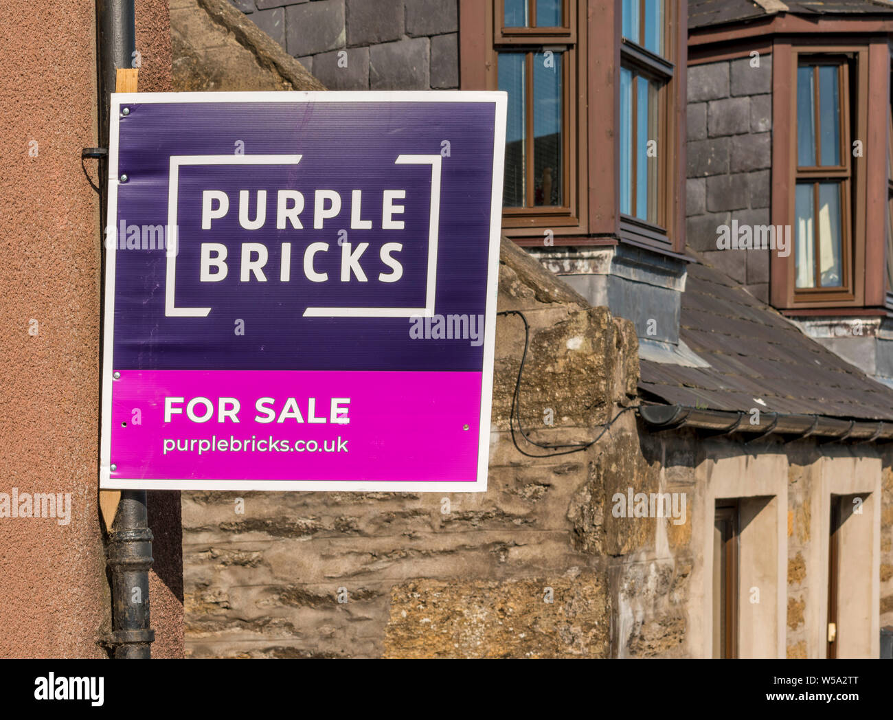 PURPLE BRICKS FOR SALE SIGN ON WALL OF A HOUSE Stock Photo
