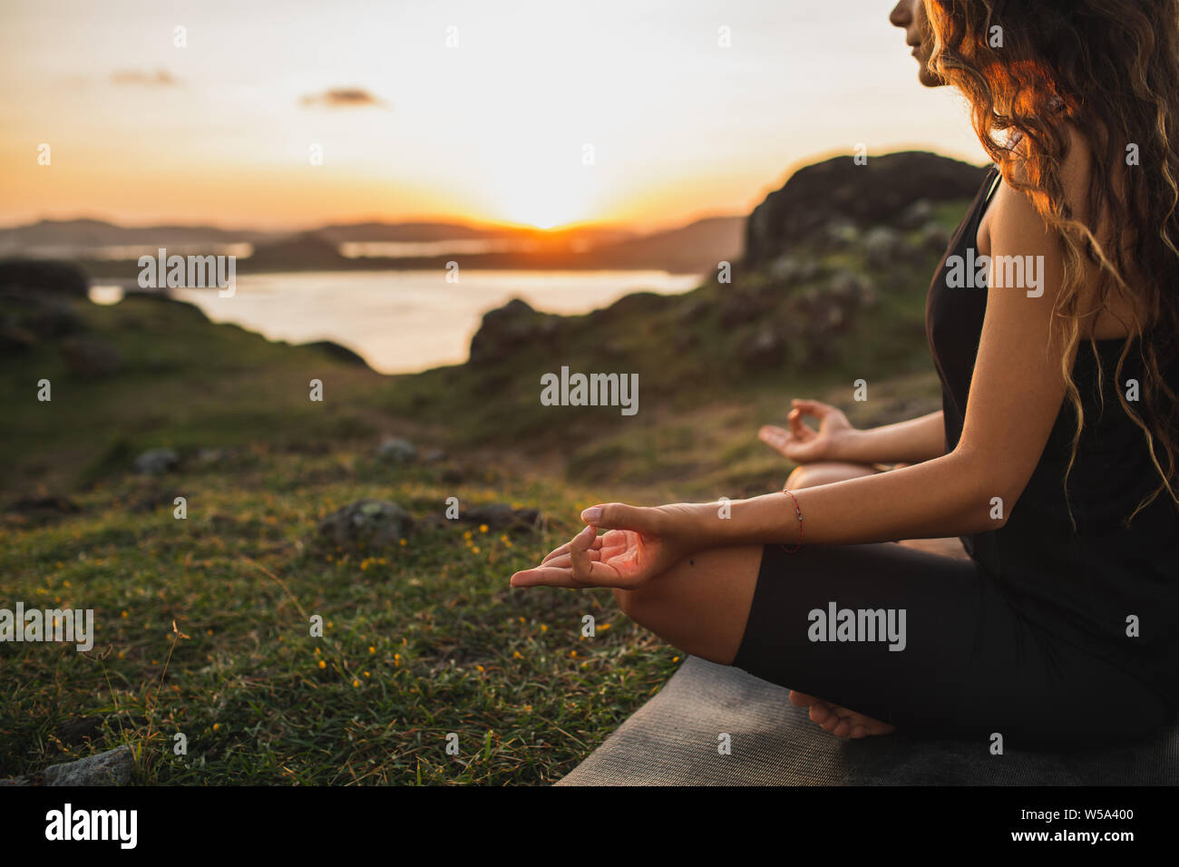 Healthy Lifestyle and Yoga Concept. Close-up hands. Woman do yoga outdoors at sunrise in lotus position. Woman exercising and meditating in morning. N Stock Photo