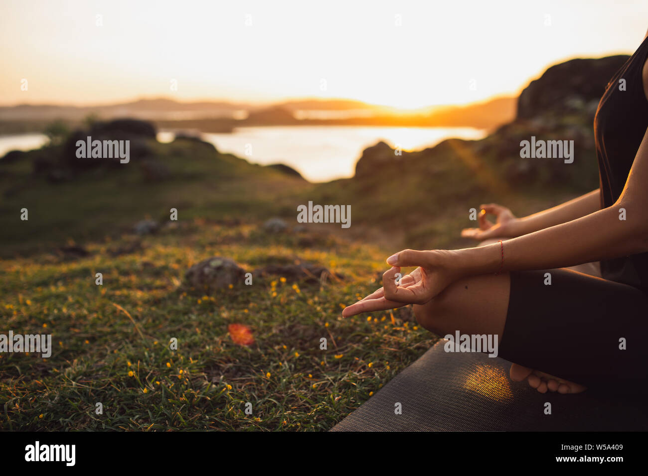 Healthy Lifestyle and Yoga Concept. Close-up hands. Woman do yoga outdoors at sunrise in lotus position. Woman exercising and meditating in morning. N Stock Photo