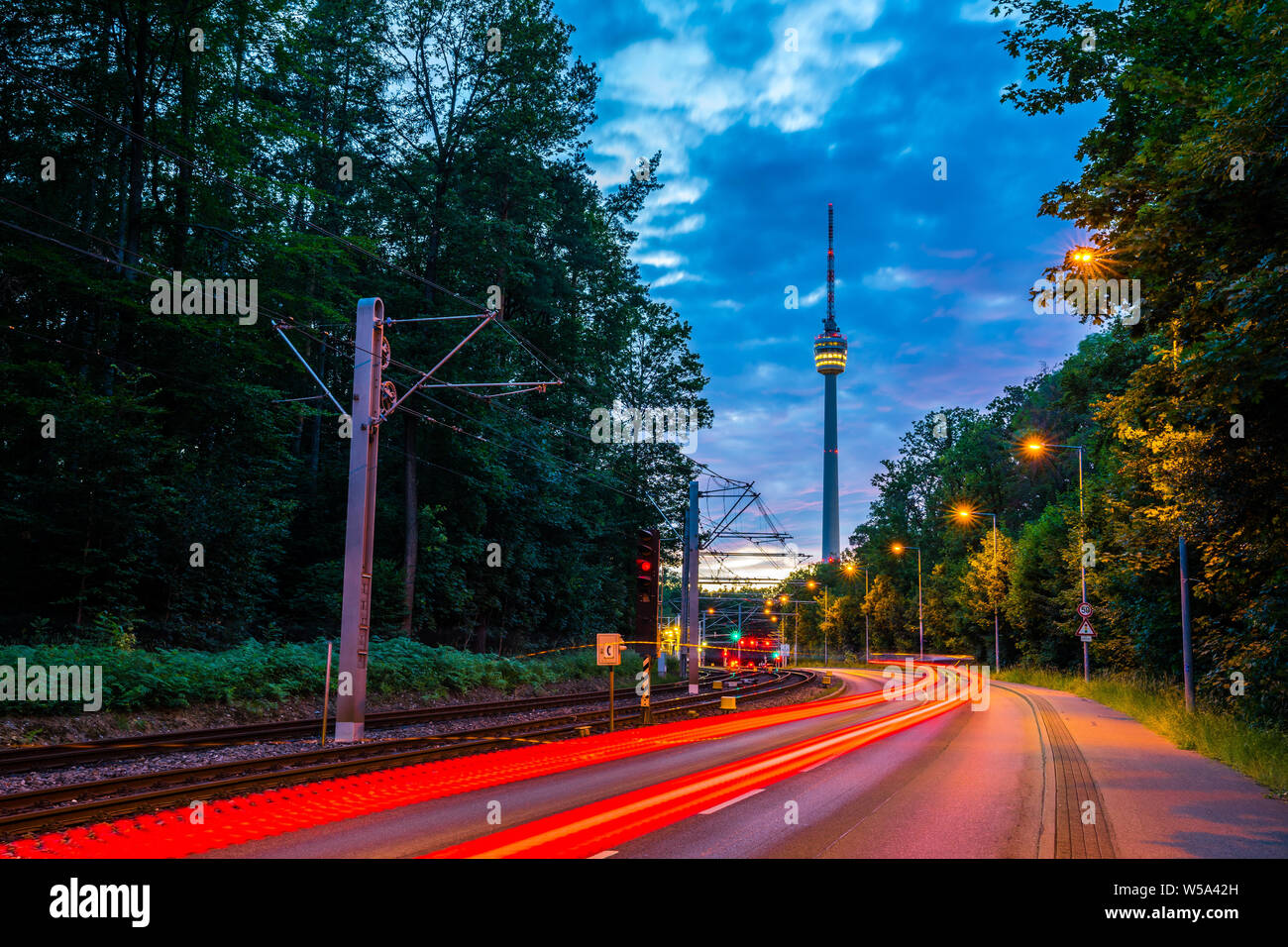 Germany, Illuminated tracer lights of cars and traffic on road to famous stuttgart television tower (tv tower) after sunset in magical twilight surrou Stock Photo