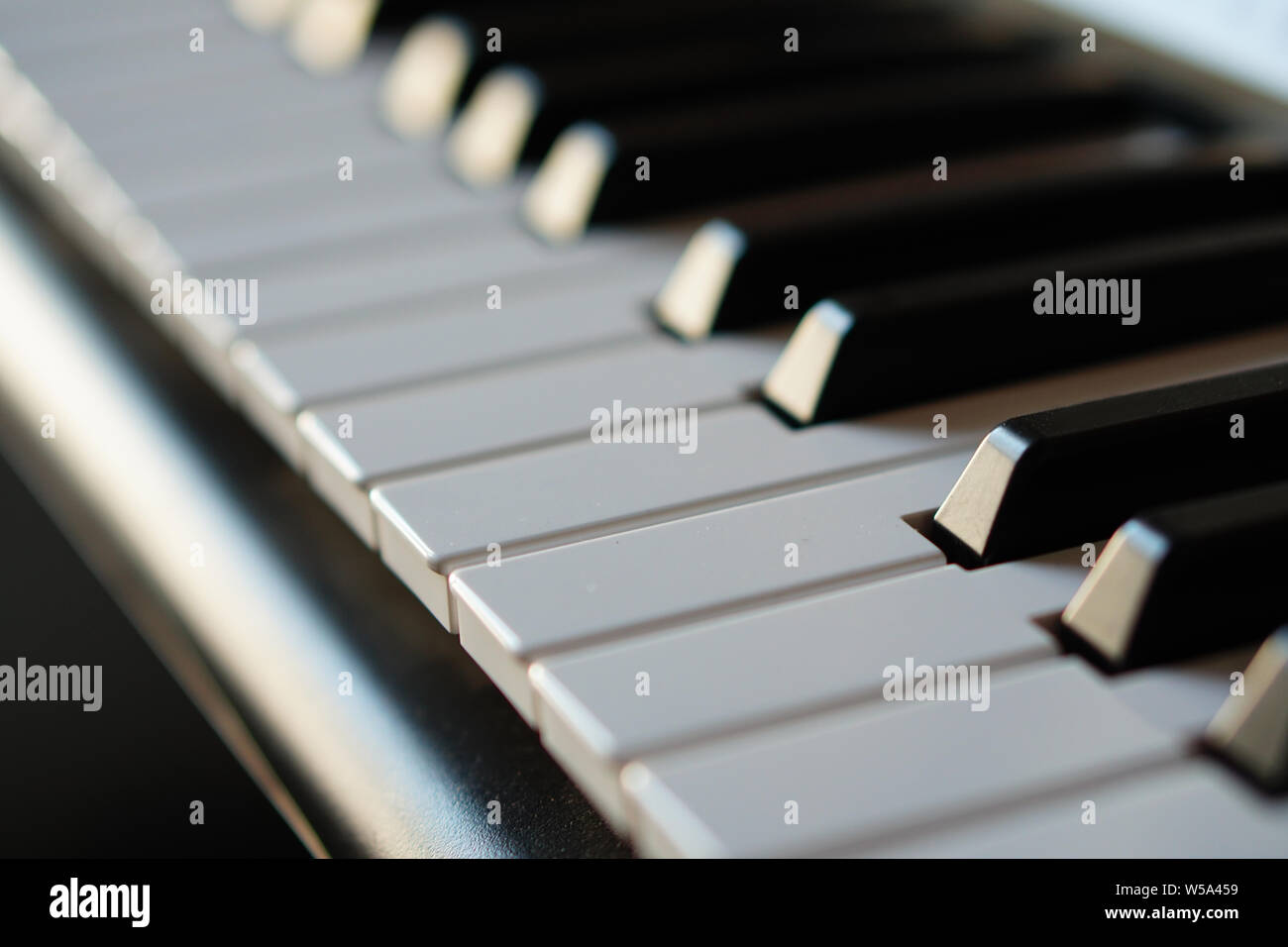 Electronic synthesizer piano keyboard in the sun's rays macro. Colored rays of light hi-tech. Stock Photo