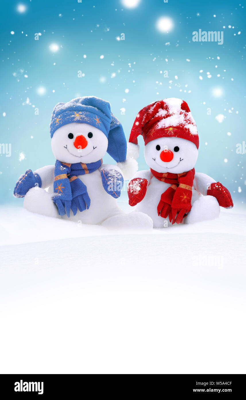Two little snowmen the girl and the boy in caps and scarfs on snow in the winter. Festive background with a funny snowman. Christmas card, copy space. Stock Photo