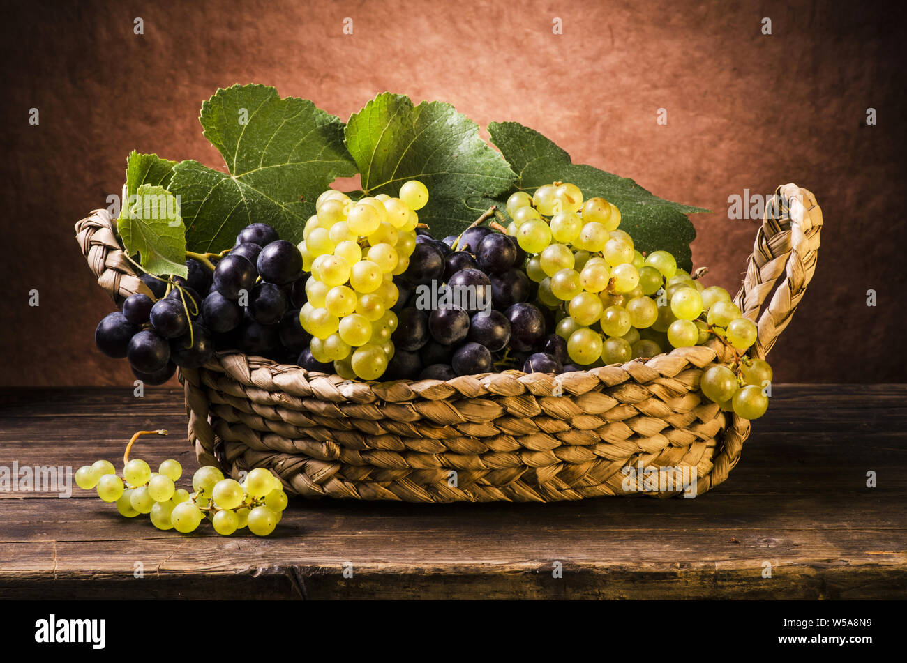 in the vintage basket white and black table grapes with leaves .still life Stock Photo