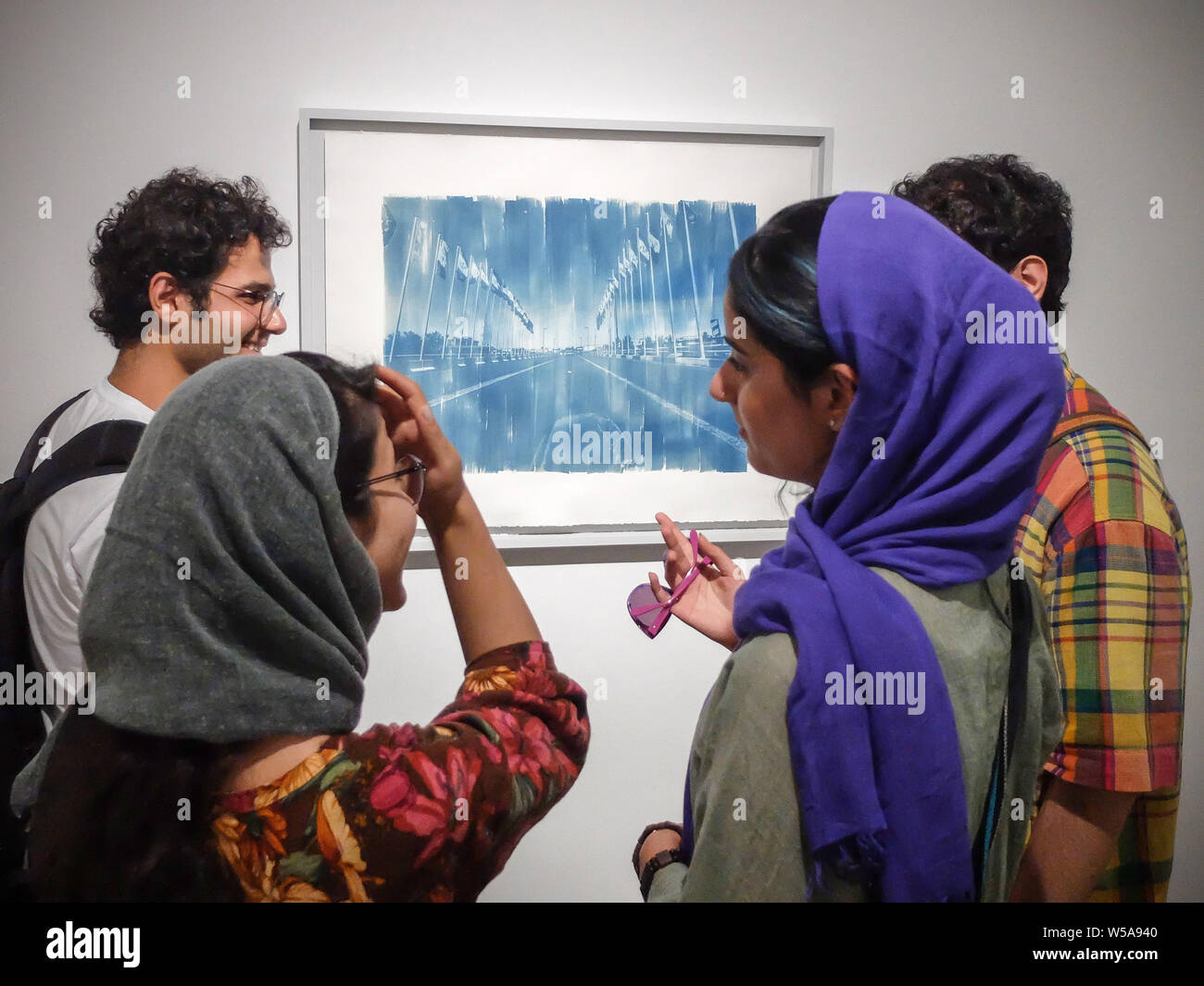 July 26, 2019, Tehran, Tehran, IRAN: People visit Vahid Dashtyari and Mehdi Khandan's photo exhibition at Mohsen Gallery in downtown Tehran, Iran. The two-man photo show by Vahid Dashtyari and Mehdi Khandan is about alternative photographic processes, namely gelatin silver, and cyanotype, to record reality: One is seeking to recover the lost spirit of photography and revert something fake to its original form, while the other is searching for the lost soul of the city, changing something authentic to a counterfeit. Credit: Rouzbeh Fouladi/ZUMA Wire/Alamy Live News Stock Photo