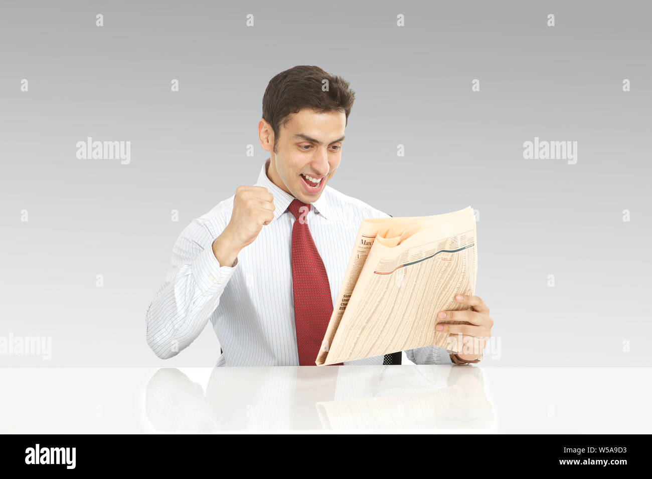 Businessman reading a newspaper and punching the air Stock Photo Alamy