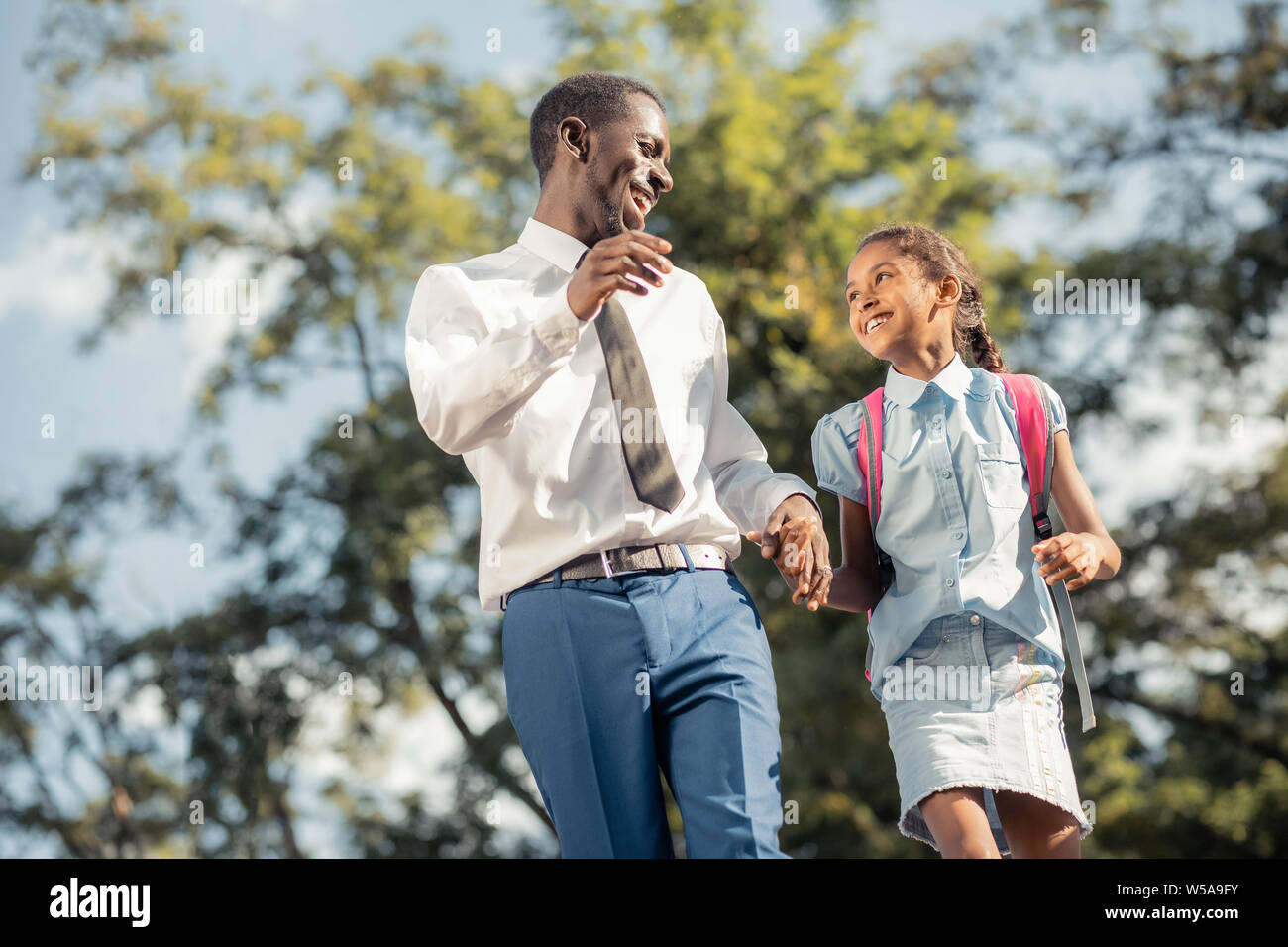 Joyful father and daughter walking hand in hand after classes Stock ...