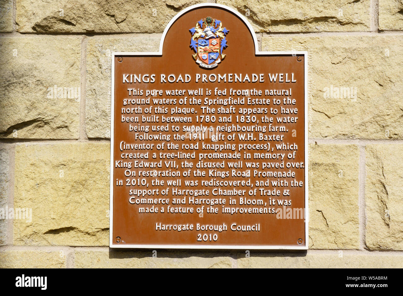 Kings Road, Promenade Well ornamental metal plaque on the wall outside The Exhibition Centre, Harrogate, North Yorkshire, England, UK.. Stock Photo