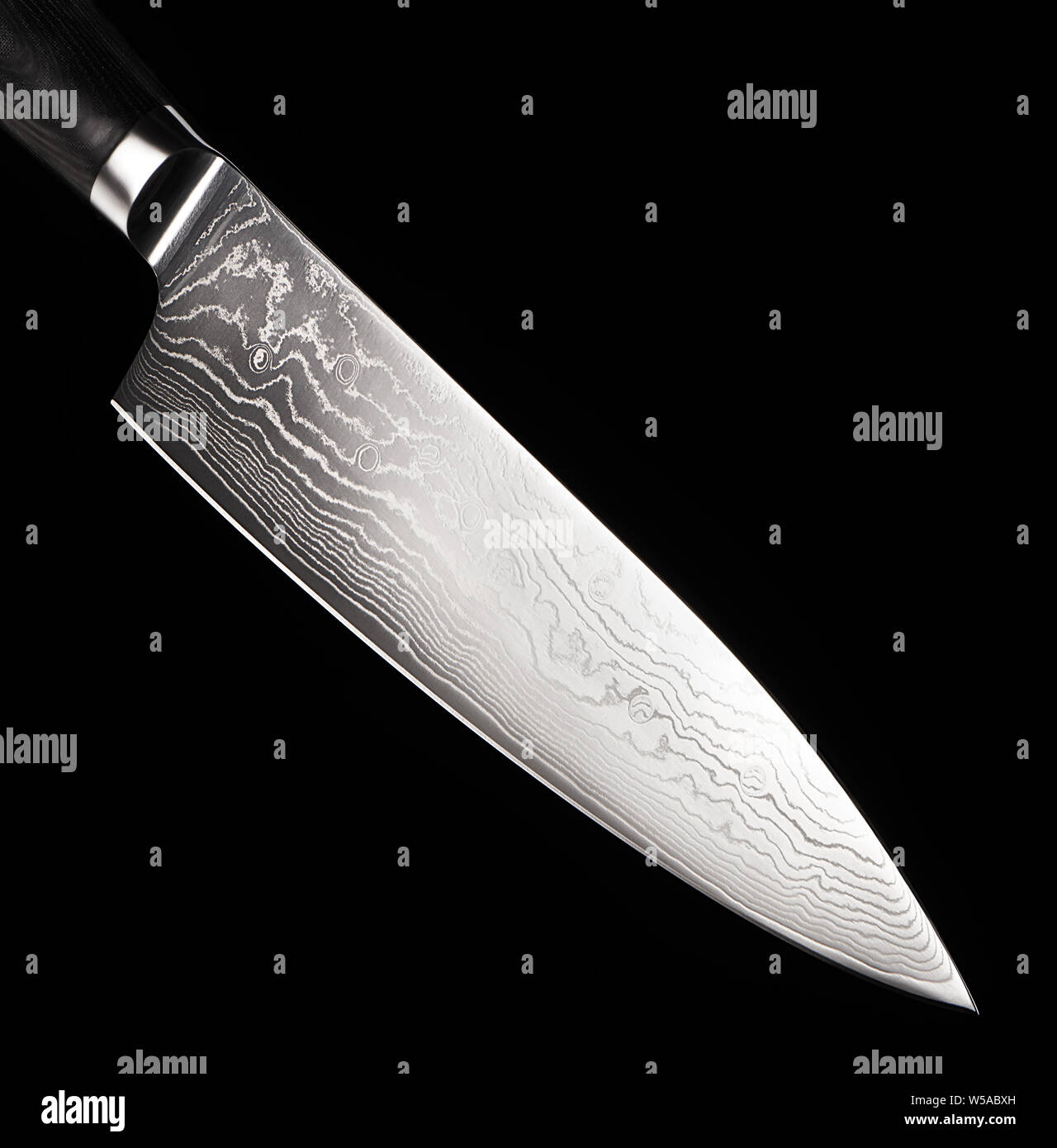 Close up of professional steel kitchen knife with black handle isolated on black background Stock Photo