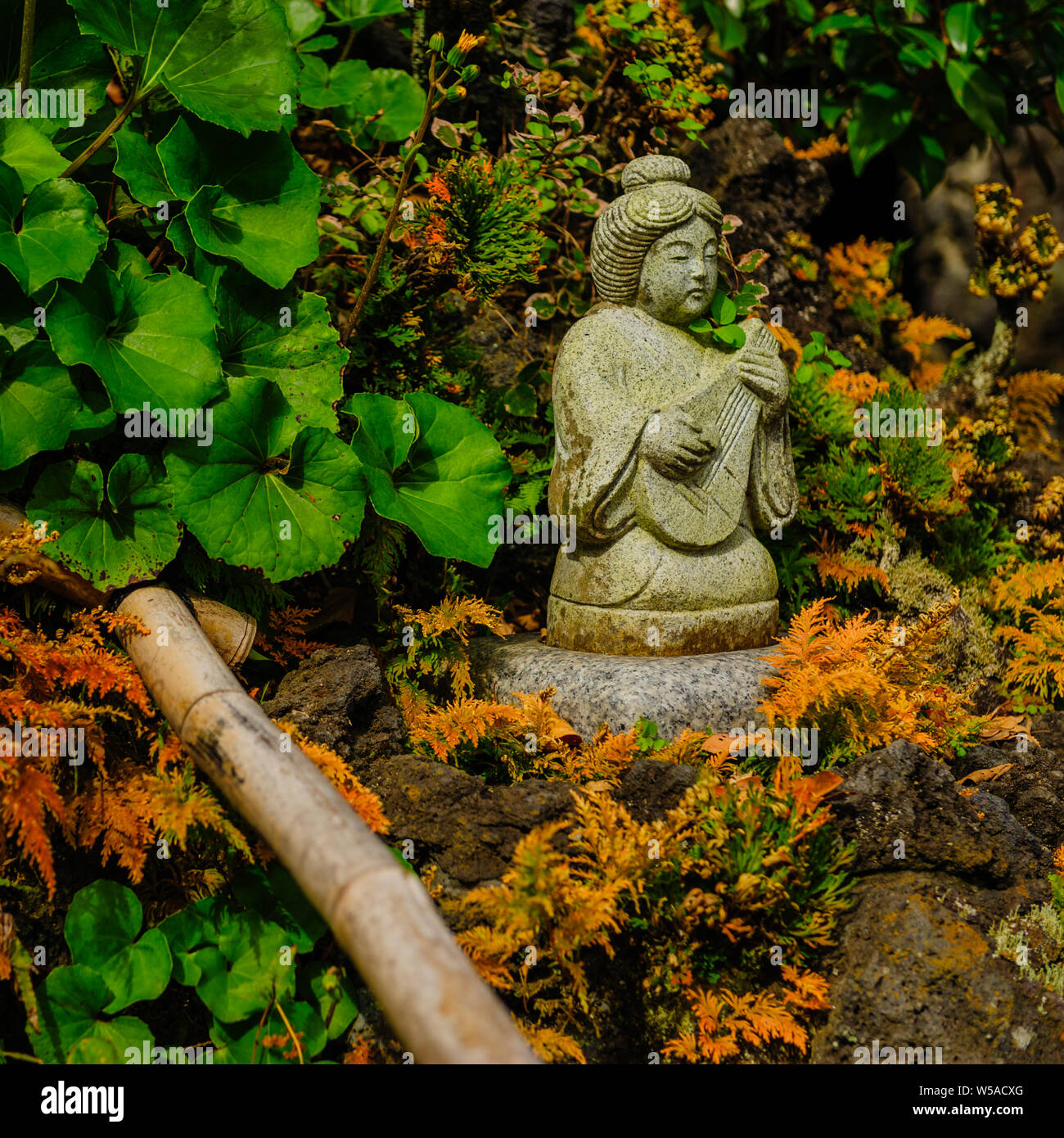 Small statue with rich detailed artwork placed on rocks surrounded by