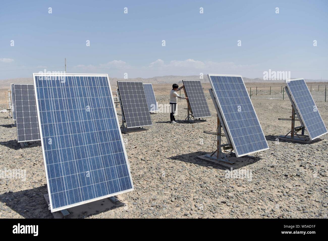(190727) -- TURPAN, July 27, 2019 (Xinhua) -- Inspector You Liwu adjusts the angle of photovoltaic panel at a photovoltaic dry-heat test area on a large patch of land of the Xinjiang Turpan Natural Environment Experimental Research Center in Turpan, northwest China's Xinjiang Uygur Autonomous Region, July 17, 2019. You Liwu, 26, has been an outdoor-exposure test inspector of the Xinjiang Turpan Natural Environment Experimental Research Center since graduation two year ago. His work is to inspect test items and monitor and gather data, who would be exposed to the torrid test land for up to five Stock Photo
