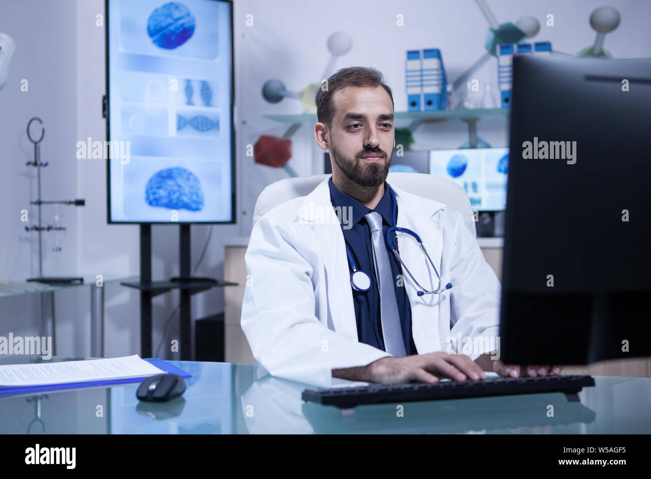Motivated handsome young doctor working on his computer in the hospital office. Specialist doctor. Stock Photo