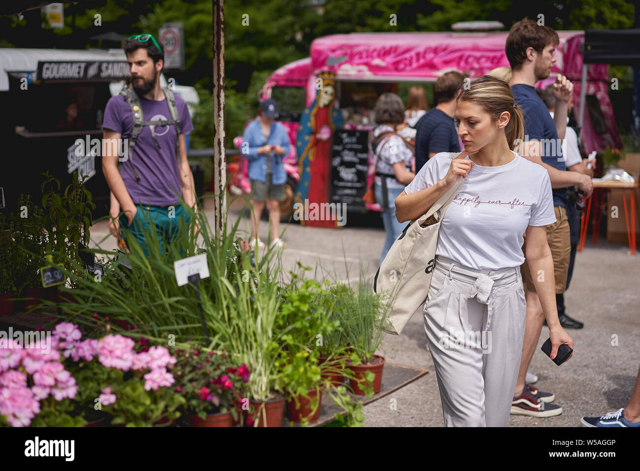 London, UK - July, 2019. Young people shopping for flowers and plants on a florist stall in Brockley market, a local farmer's market. Stock Photo