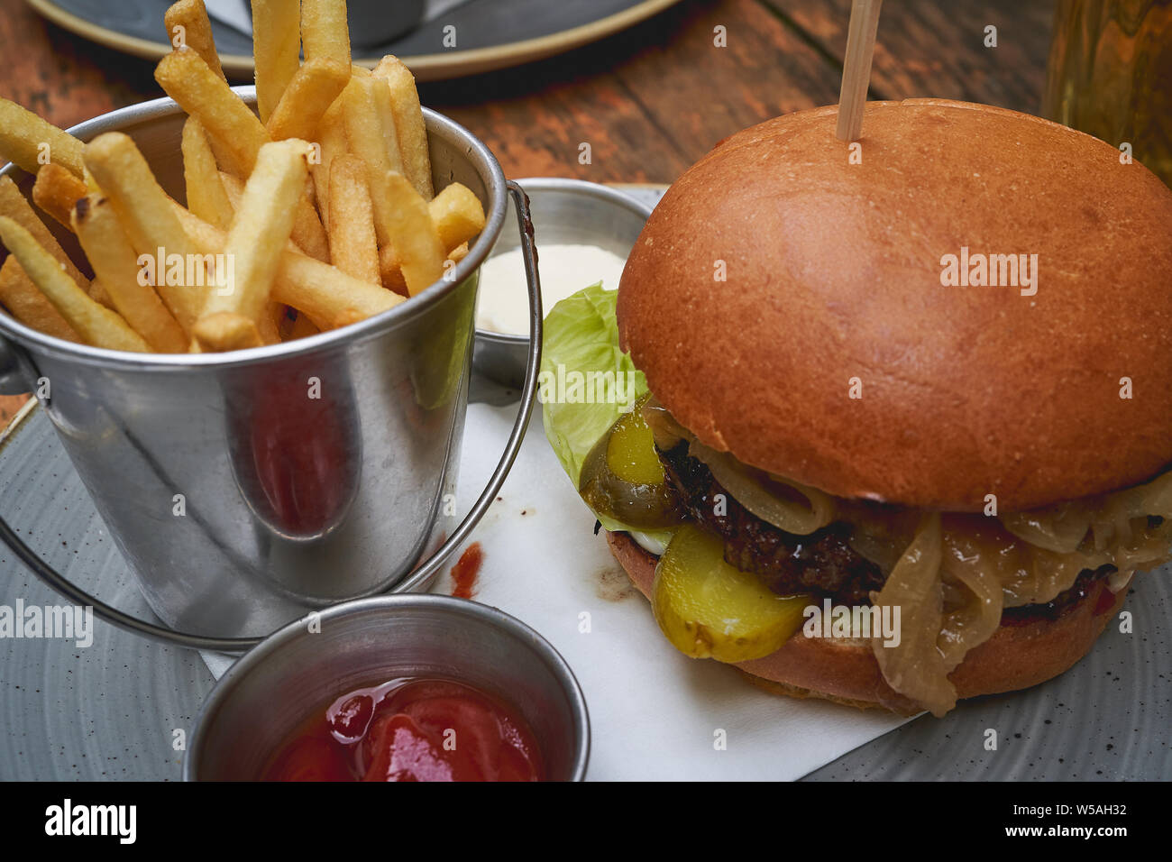 Closeup view of a beef burger with cheddar, pickles, lettuce and