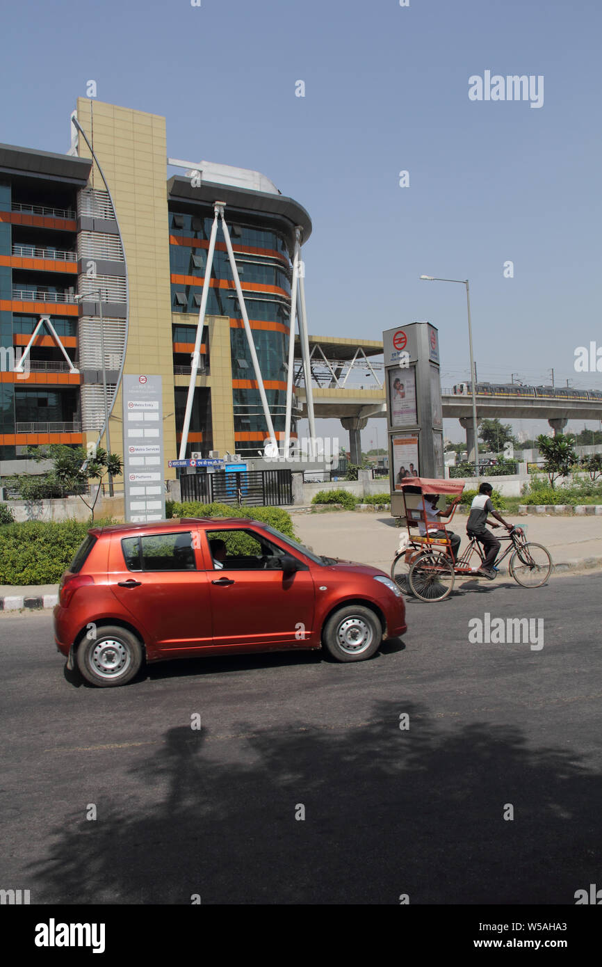 Car on the road with metro station in the background, Gurgaon, Haryana, India Stock Photo