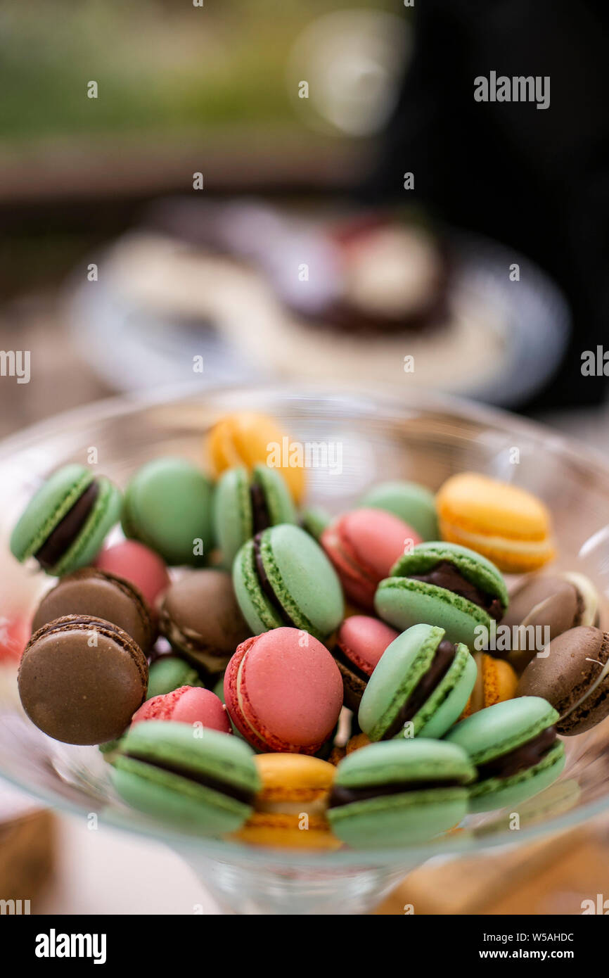 Bowl filled with assorted macaroons in green, orange, brown and yellow colour. Portrait format. Stock Photo
