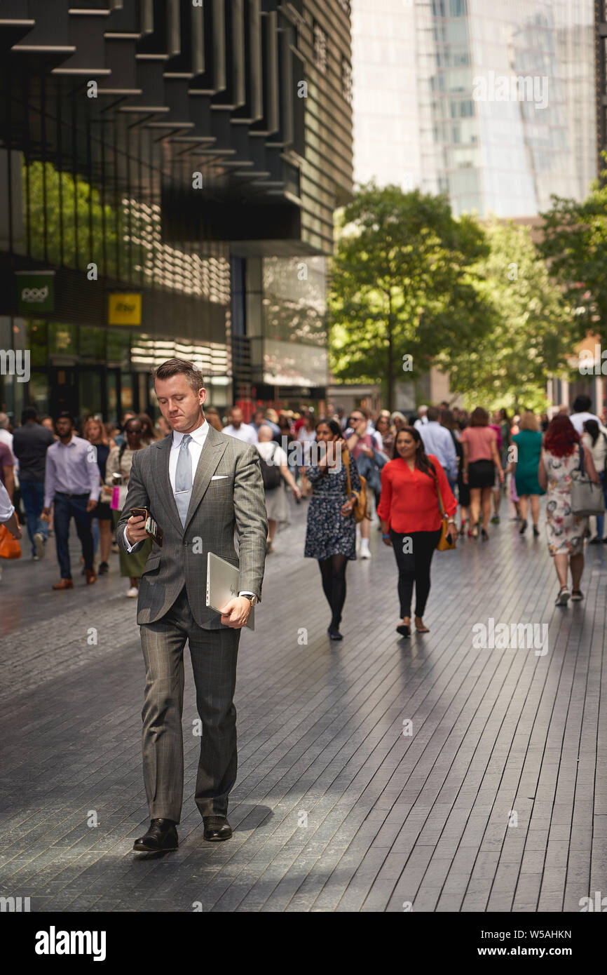 London, UK - July, 2019. A business man in suit walking along One More London, an office complex near the City Hall. Stock Photo