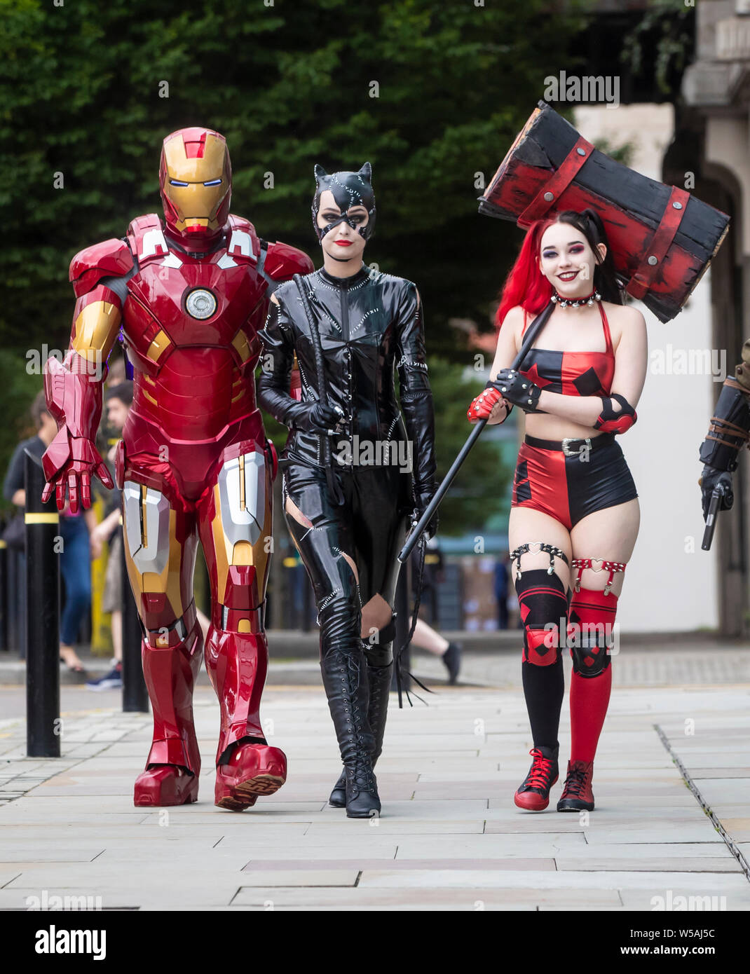 People dressed as characters (left to right) Iron Man, Cat woman and Harley Quinn from New 52 comics during the MCM Manchester Comic Con which see thousands of sci-fi fans, gamers, comic collectors, movie buffs and anime enthusiasts visit Manchester Central. Stock Photo
