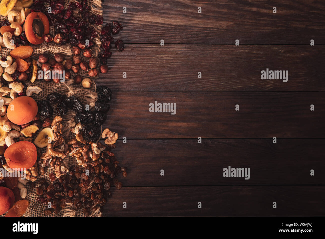 Mix of dried fruit and nuts arranged on linen fabric and an old table. Composition in the old style with a view from the top and copy space for your t Stock Photo