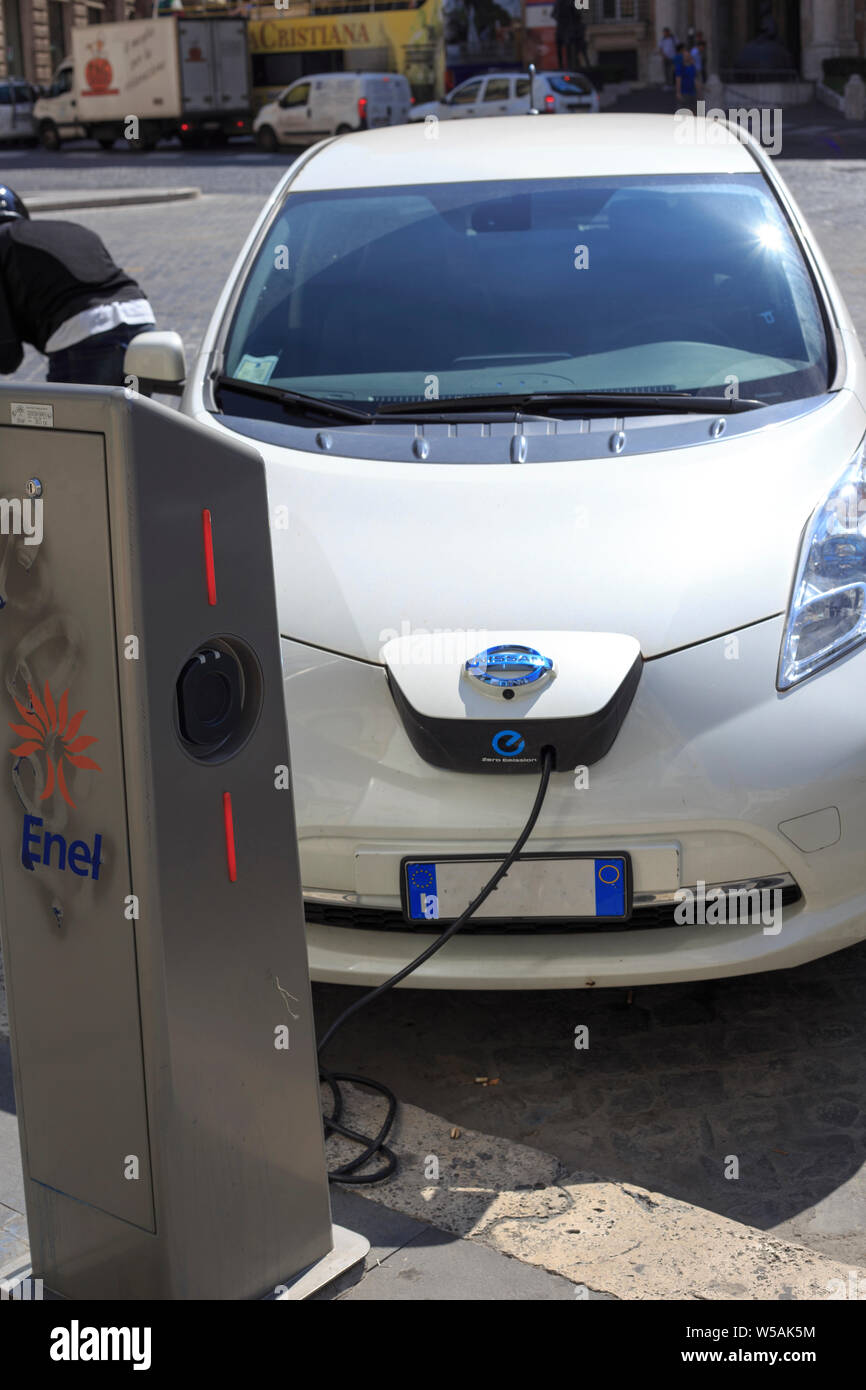Rome, Italy - September 5, 2015: a Nissan electric car is connected to a charging station. The car is being charged and runs on electricity. Stock Photo