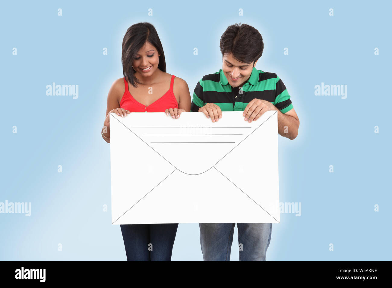 Couple holding an envelope and smiling Stock Photo