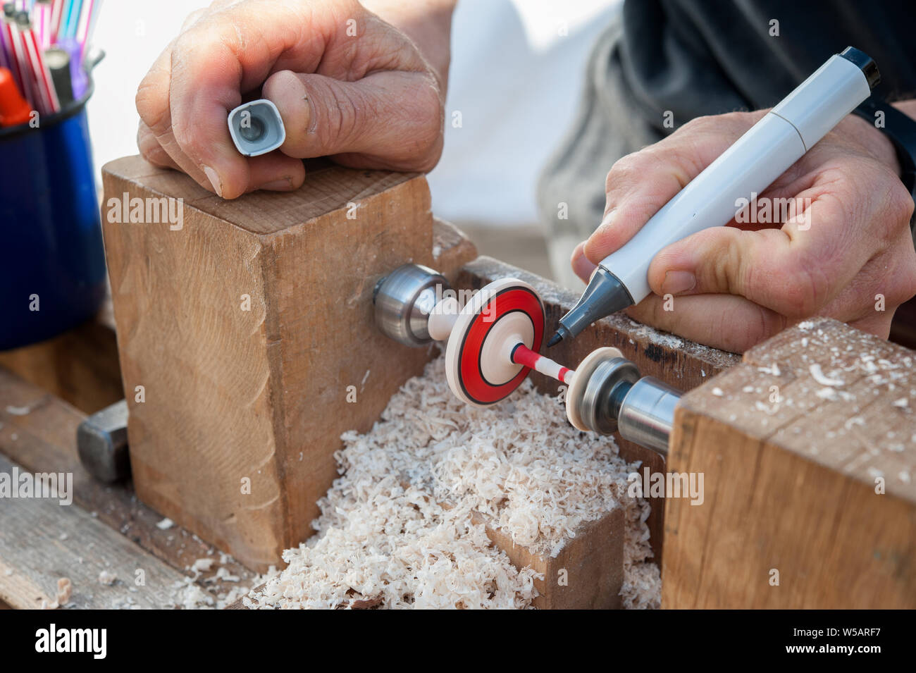 Lathe operator paints a wood top using a marker pen. Stock Photo