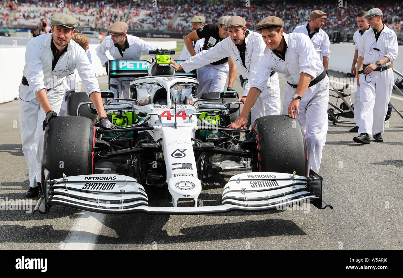 Hockenheim, Germany. 27th July, 2019. Motorsport: Formula 1 World Championship, Grand Prix of Germany. Mechanics in historical suits and sliding caps push the car of Lewis Hamilton from Great Britain by the Hockenheim, Germany. 27th July, 2019. Motorsport: Formula 1 World Championship, Grand Prix of Germany. Mechanics in historical suits and sliding caps push the car of Lewis Hamilton from Great Britain by the