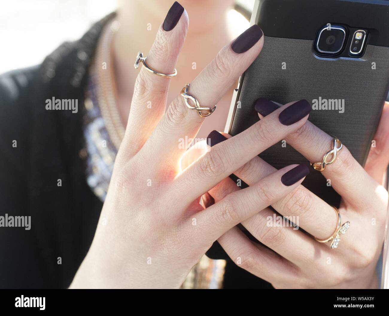 Female with black nail polish and chain-like rings holding a smartphone  Stock Photo - Alamy